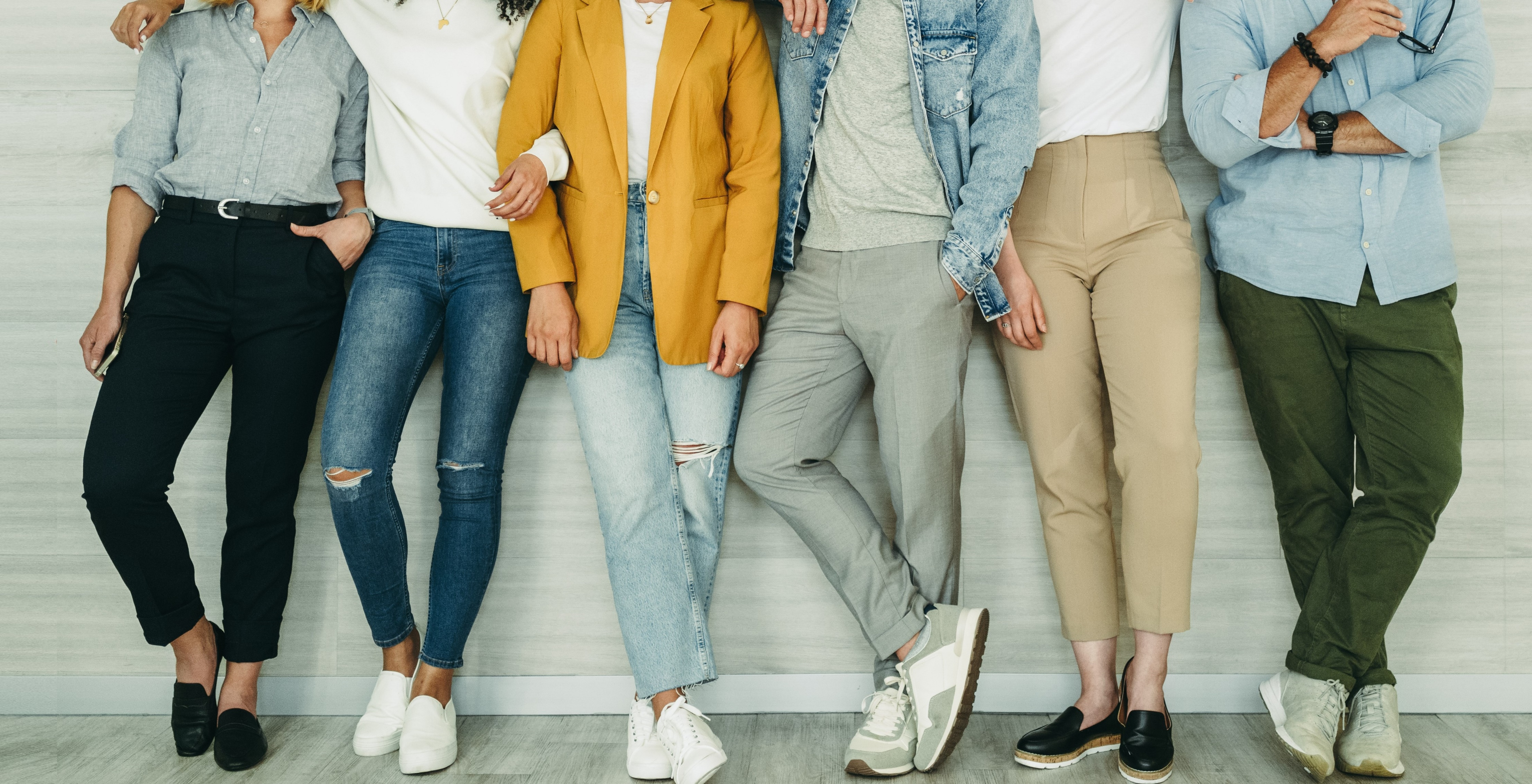 A diverse group of individuals standing next to each other against a wall.